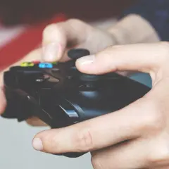 Dłonie trzymające kontroler, gotowe do gry. Wspomnienie dawnych, emocjonujących **starych gier na telefon**.