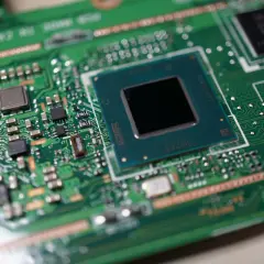 Zbliżenie na zieloną płytę główną laptopa z widocznym procesorem, gotowym do wymiany.