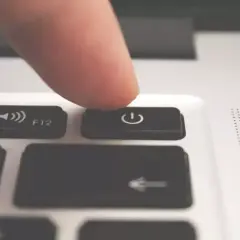 Palec naciska przycisk zasilania, inicjując automatyczne wyłączanie komputera.