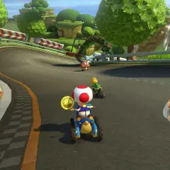 Wyścig w Mario Kart na PS5: Toad na drugim miejscu zbiera monety, a za nim jedzie Yoshi.