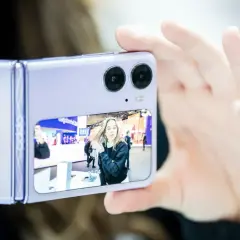 Fioletowy składany telefon z podwójnym aparatem robi zdjęcie dziewczynie. Czy to ten telefon ma najlepszy aparat?