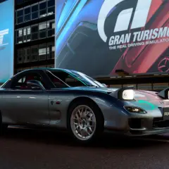 Srebrne RX-7 z podniesionymi światłami, gotowe do jazdy w Gran Turismo 7.