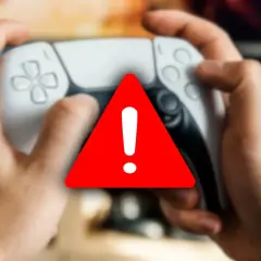 Ręce trzymające kontroler PlayStation, na którym widnieje czerwony trójkąt z wykrzyknikiem, symbolizujący awarię.