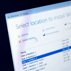 Instalator Windows 11 pokazuje opcje zarządzania partycjami. Kursor myszy wskazuje "Usuń partycję", przygotowując do formatowania dysku.