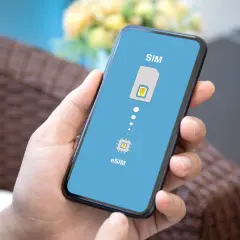 Dłoń trzyma smartfon z ekranem pokazującym przejście od tradycyjnej karty SIM do technologii eSIM.