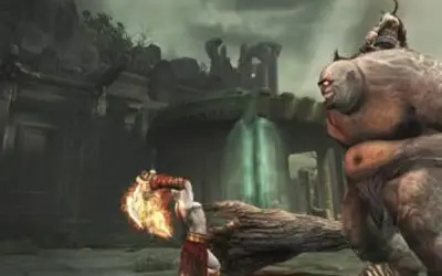 Kratos z płonącym ostrzem walczy z olbrzymim potworem w mrocznym świecie God of War 2.