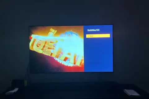 Na ekranie telewizora logo anime z niebieskimi napisami. Menu wyboru napisów pokazuje "None", ale szukam opcji "crunchyroll polskie napisy".