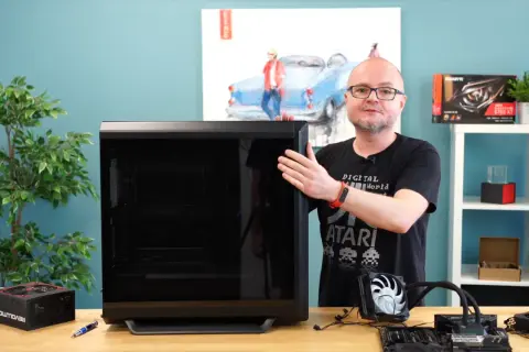 Mężczyzna pokazuje obudowę komputera, obok leży zasilacz i elementy do złożenia PC. Poradnik: jak złożyć komputer.