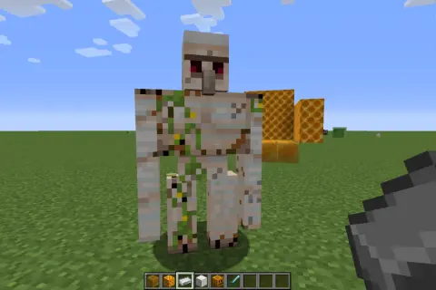 Żelazny golem stoi na trawie, obok plastrów miodu. Jak zdobyć krzemień w Minecraft?