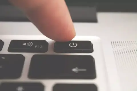 Palec naciska przycisk zasilania, inicjując automatyczne wyłączanie komputera.