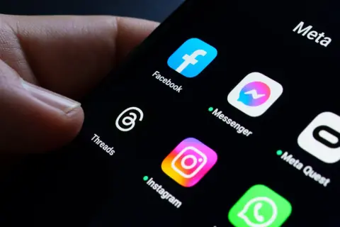 Palec dotyka ekranu telefonu z ikonami aplikacji Meta: Facebook, Messenger, Instagram, Threads. Awaria Facebooka sprawia, że użytkownicy szukają alternatyw.
