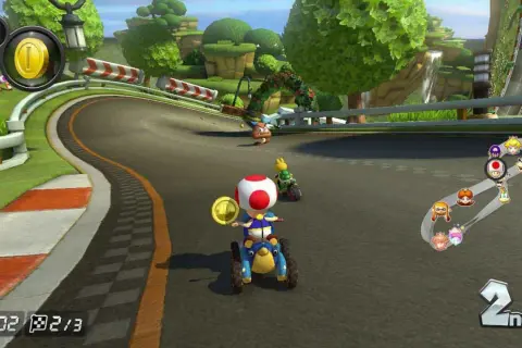 Wyścig w Mario Kart na PS5: Toad na drugim miejscu zbiera monety, a za nim jedzie Yoshi.