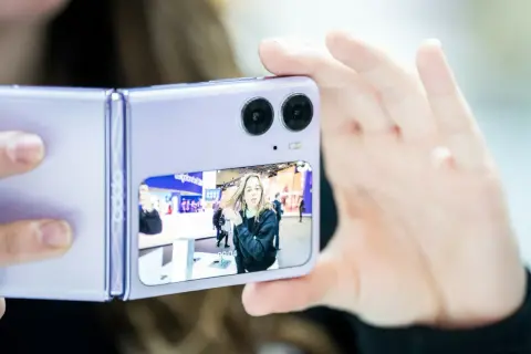 Fioletowy składany telefon z podwójnym aparatem robi zdjęcie dziewczynie. Czy to ten telefon ma najlepszy aparat?