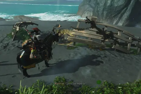 Samuraj na koniu szuka pomocnej dłoni w Ghost of Tsushima, zbliżając się do wraku statku na plaży.