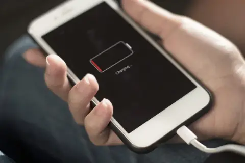 Dłoń trzyma telefon z ikoną niskiego poziomu baterii. Zastanawiasz się, power bank 50000 mah na ile starcza?
