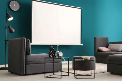 Nowoczesny salon z szarymi sofami i dużym ekranem do projektora. Idealne miejsce na domowe kino.