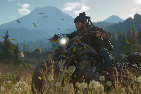 Deacon z Days Gone 2 pędzi motocyklem przez łąkę, a wokół latają liście.