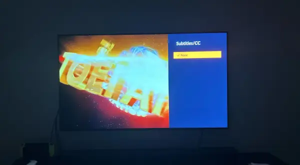 Na ekranie telewizora logo anime z niebieskimi napisami. Menu wyboru napisów pokazuje "None", ale szukam opcji "crunchyroll polskie napisy".