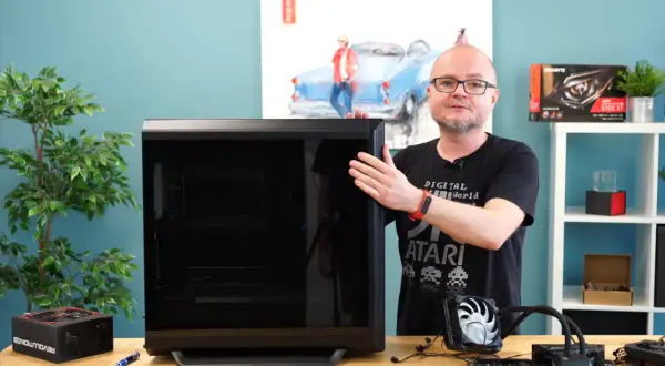 Mężczyzna pokazuje obudowę komputera, obok leży zasilacz i elementy do złożenia PC. Poradnik: jak złożyć komputer.