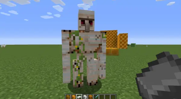 Żelazny golem stoi na trawie, obok plastrów miodu. Jak zdobyć krzemień w Minecraft?