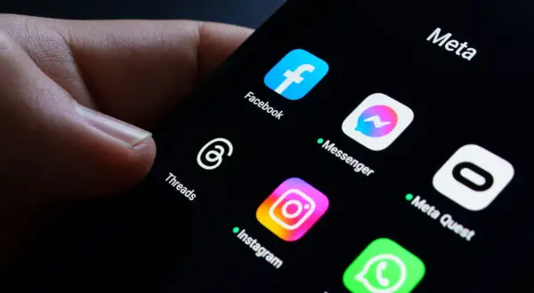 Palec dotyka ekranu telefonu z ikonami aplikacji Meta: Facebook, Messenger, Instagram, Threads. Awaria Facebooka sprawia, że użytkownicy szukają alternatyw.