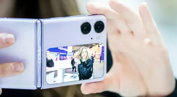 Fioletowy składany telefon z podwójnym aparatem robi zdjęcie dziewczynie. Czy to ten telefon ma najlepszy aparat?