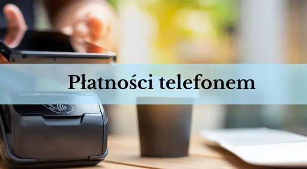 Zbliżenie na terminal płatniczy i kubek kawy. Dłoń trzyma smartfon, gotowa do płatności telefonem.