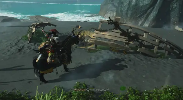 Samuraj na koniu szuka pomocnej dłoni w Ghost of Tsushima, zbliżając się do wraku statku na plaży.
