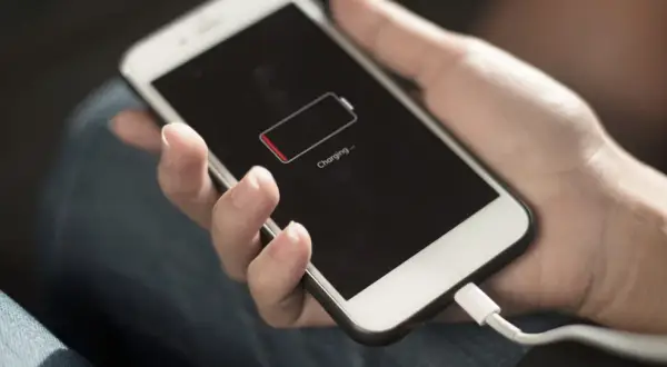 Dłoń trzyma telefon z ikoną niskiego poziomu baterii. Zastanawiasz się, power bank 50000 mah na ile starcza?
