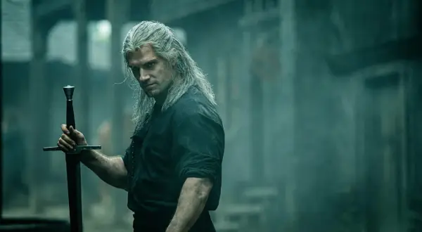 Geralt z Rivii, **the witcher**, z długimi, siwymi włosami i mieczem w dłoni, spogląda groźnie.