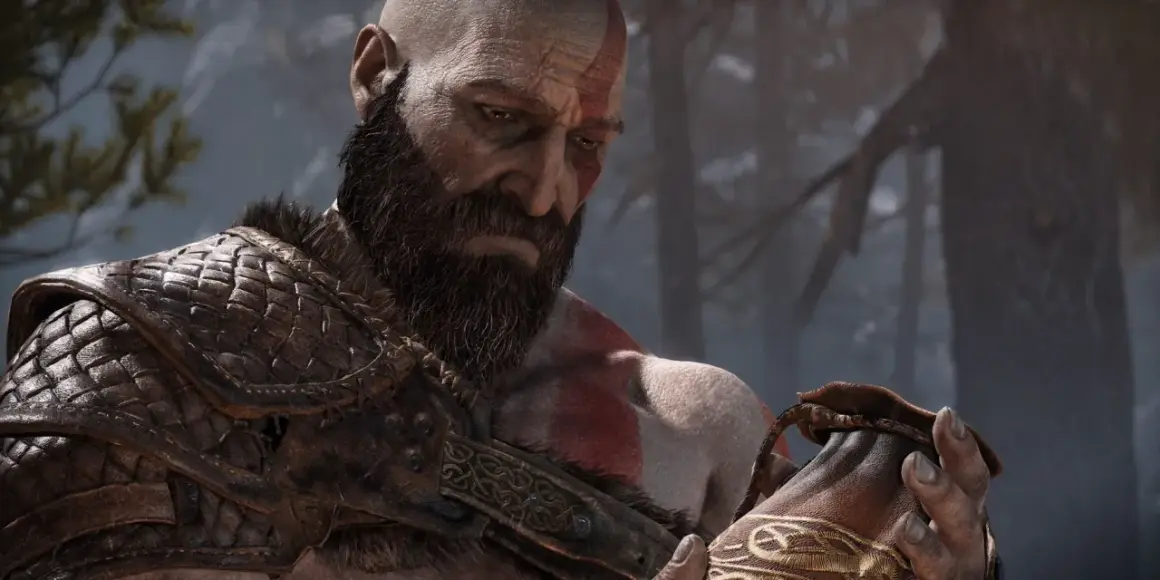 Kratos z brodą i czerwonymi znakami na twarzy, w zbroi, trzyma sakiewkę. Dzieło Santa Monica Studio.