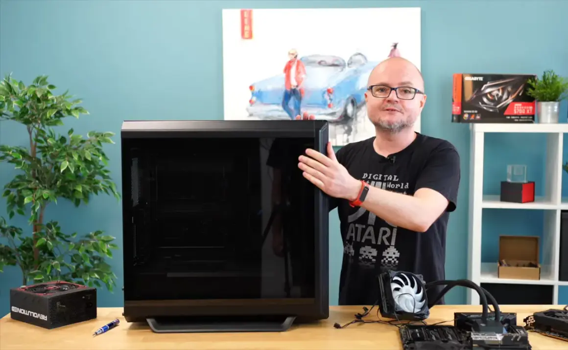 Mężczyzna pokazuje obudowę komputera, obok leży zasilacz i elementy do złożenia PC. Poradnik: jak złożyć komputer.