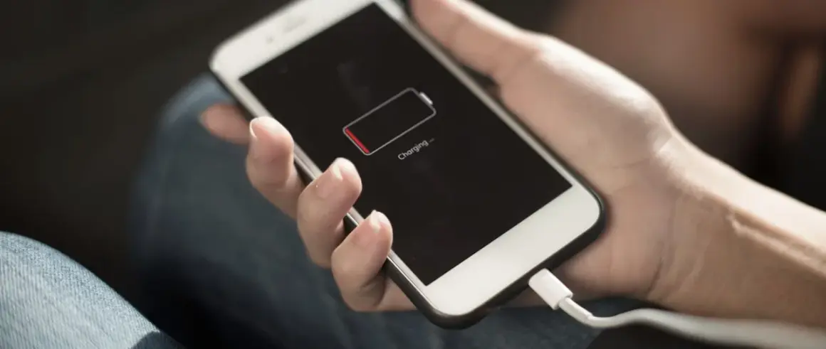 Dłoń trzyma telefon z ikoną niskiego poziomu baterii. Zastanawiasz się, power bank 50000 mah na ile starcza?