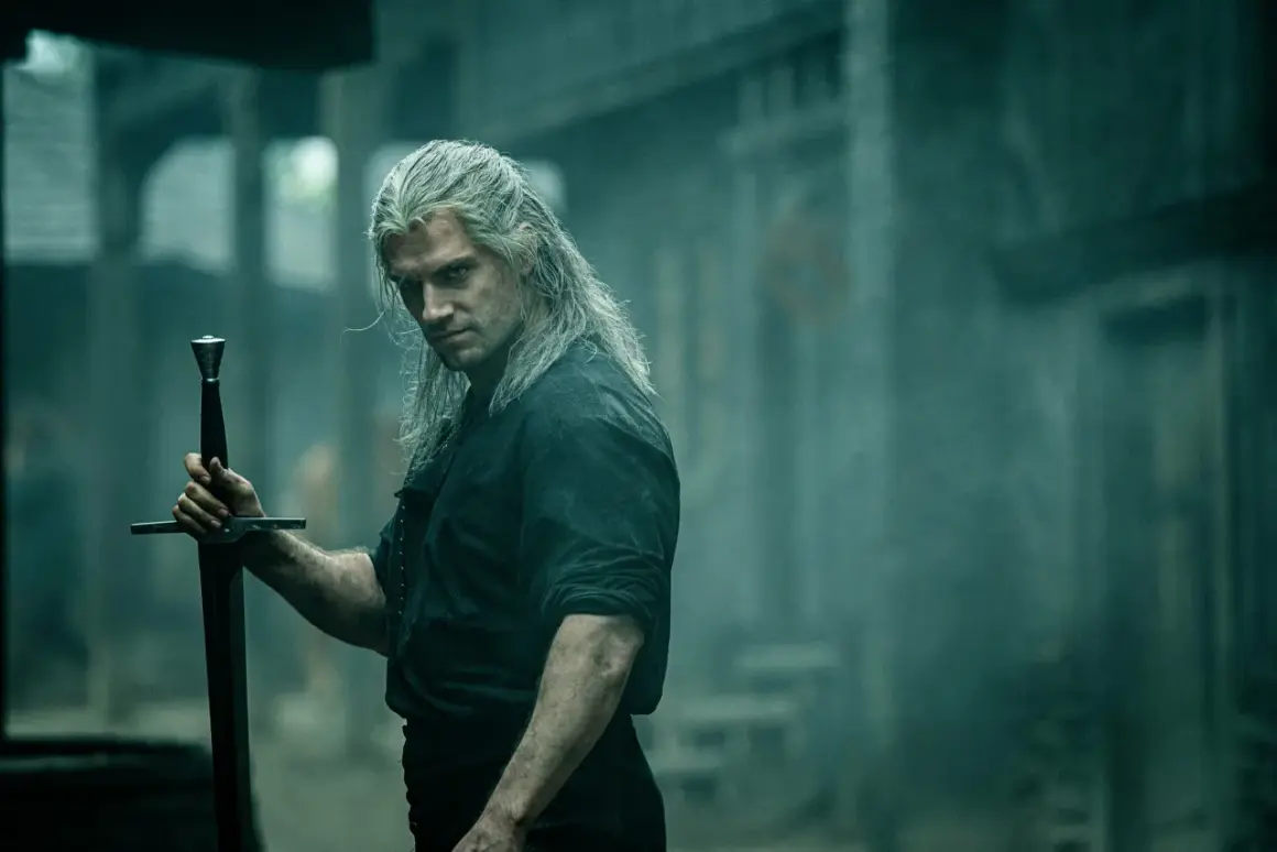 Geralt z Rivii, **the witcher**, z długimi, siwymi włosami i mieczem w dłoni, spogląda groźnie.