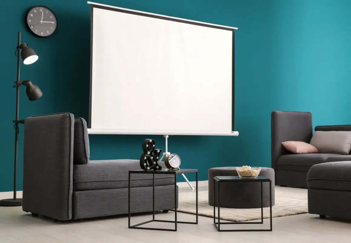 Nowoczesny salon z szarymi sofami i dużym ekranem do projektora. Idealne miejsce na domowe kino.