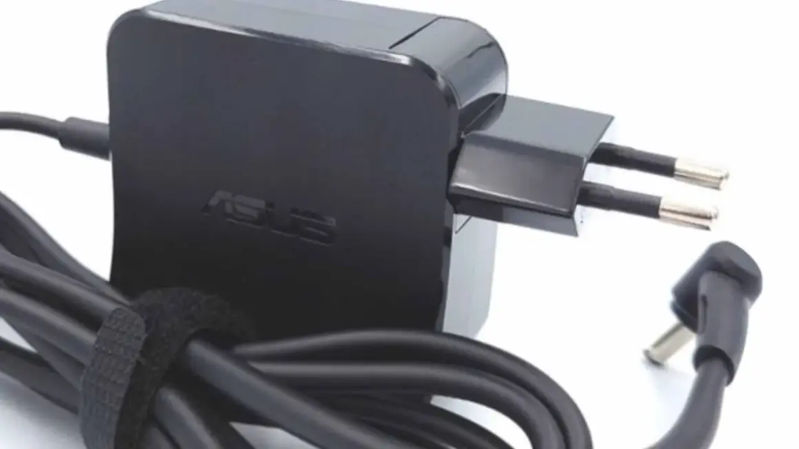 Czarny zasilacz Asus z wtyczką europejską i kablem. Dowiedz się, jak dobrać zasilacz do laptopa, by zapewnić mu bezpieczne ładowanie.