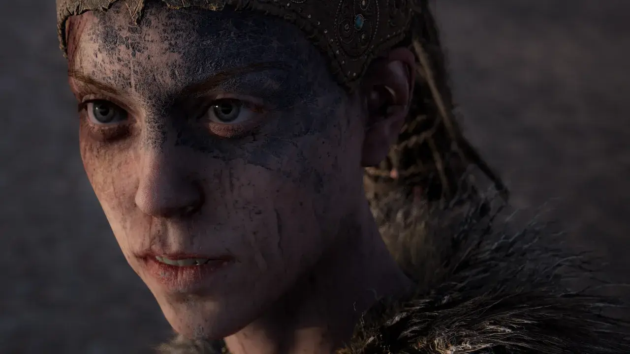 Senua z gry Hellblade: Senua's Sacrifice z makijażem wojennym i opaską na głowie, patrzy z determinacją.