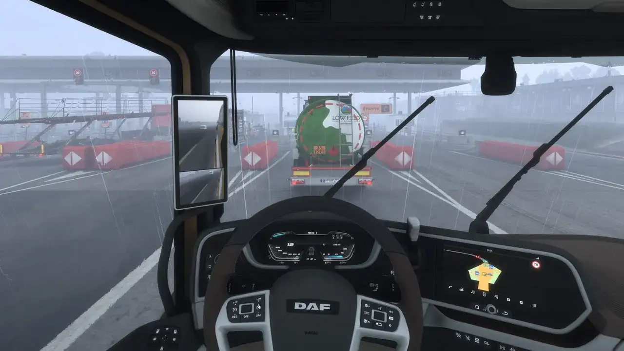 Widok z kabiny ciężarówki w Euro Truck Simulator 2 na PS5. Deszczowa pogoda, przejazd przez bramki.
