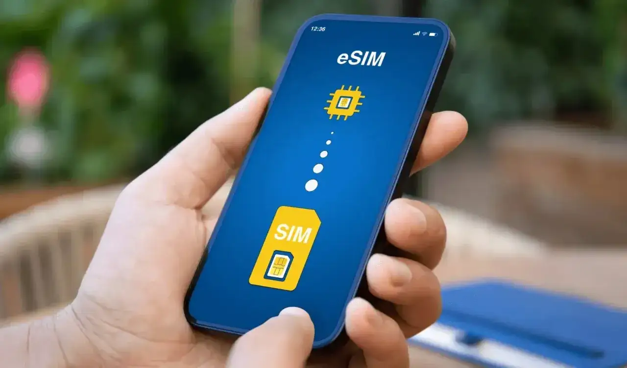 Dłoń trzyma smartfon z ekranem pokazującym przejście od tradycyjnej karty SIM do technologii eSIM.