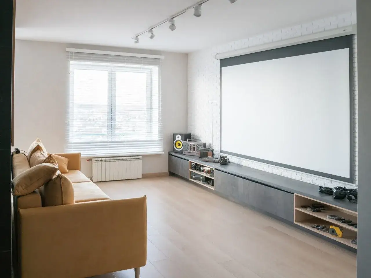 Nowoczesny salon z kanapą i wielkim ekranem. Projektor zamiast TV oferuje kinowe wrażenia w domu.