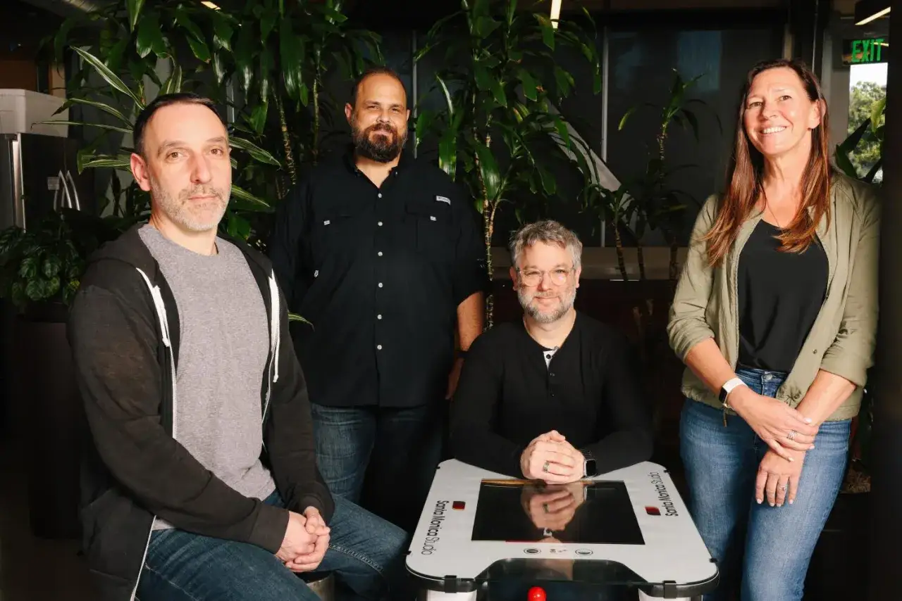 Zespół z Santa Monica Studio pozuje przy konsoli do gier.