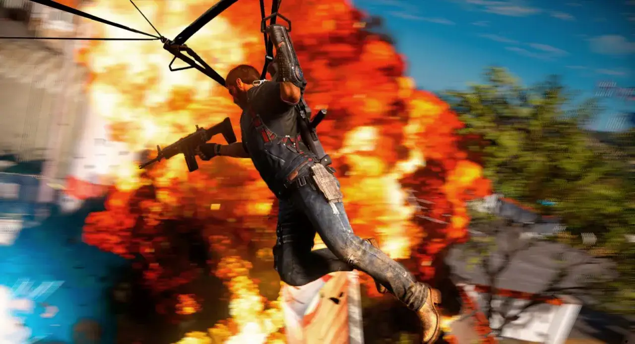 Rico Rodriguez w akcji, z karabinem w ręku, na tle potężnej eksplozji. Gra Just Cause 3 wymaga mocnego sprzętu.