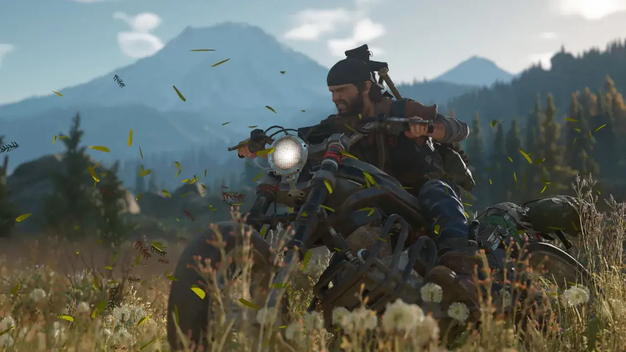Deacon z Days Gone 2 pędzi motocyklem przez łąkę, a wokół latają liście.