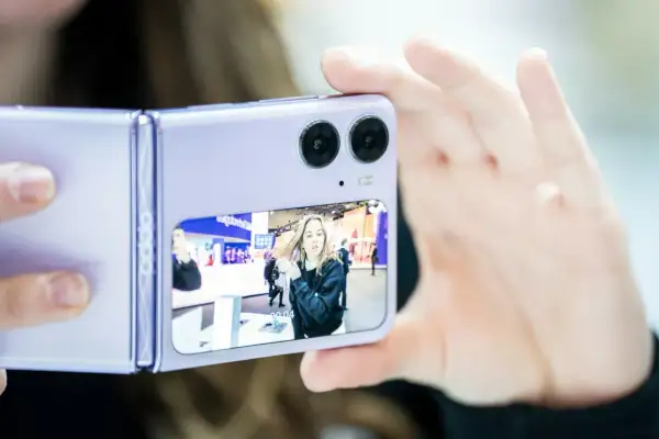 Fioletowy składany telefon z podwójnym aparatem robi zdjęcie dziewczynie. Czy to ten telefon ma najlepszy aparat?