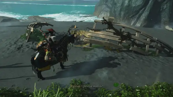 Samuraj na koniu szuka pomocnej dłoni w Ghost of Tsushima, zbliżając się do wraku statku na plaży.