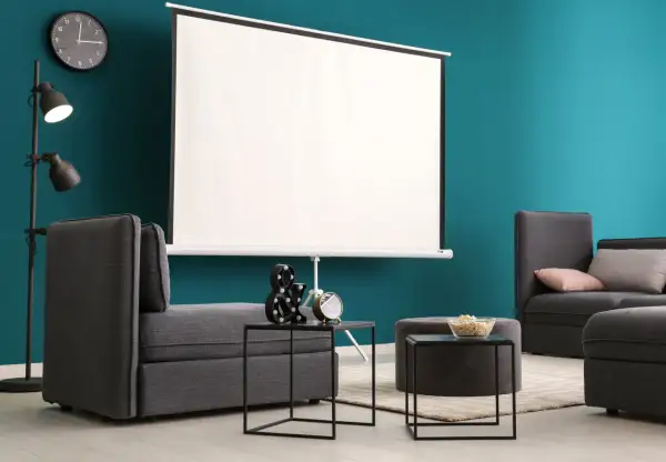 Nowoczesny salon z szarymi sofami i dużym ekranem do projektora. Idealne miejsce na domowe kino.